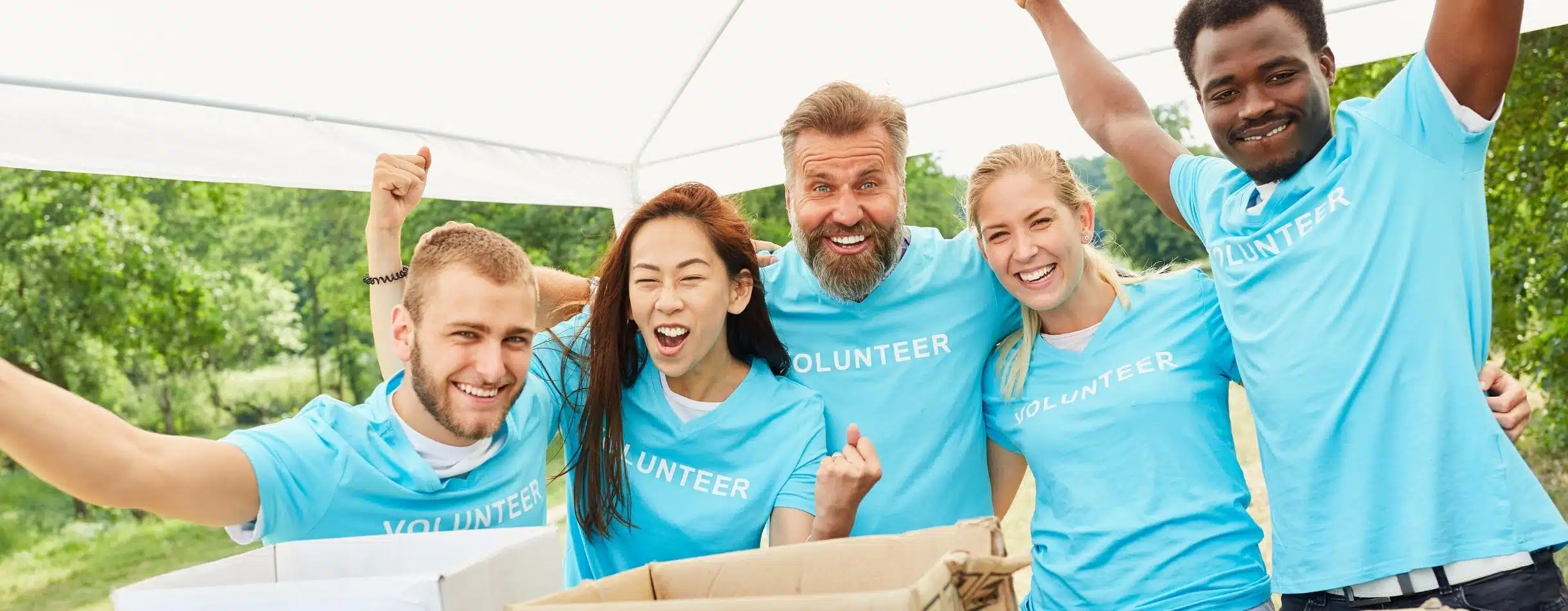 Five volunteers cheering around a table with boxes for their donation drive.