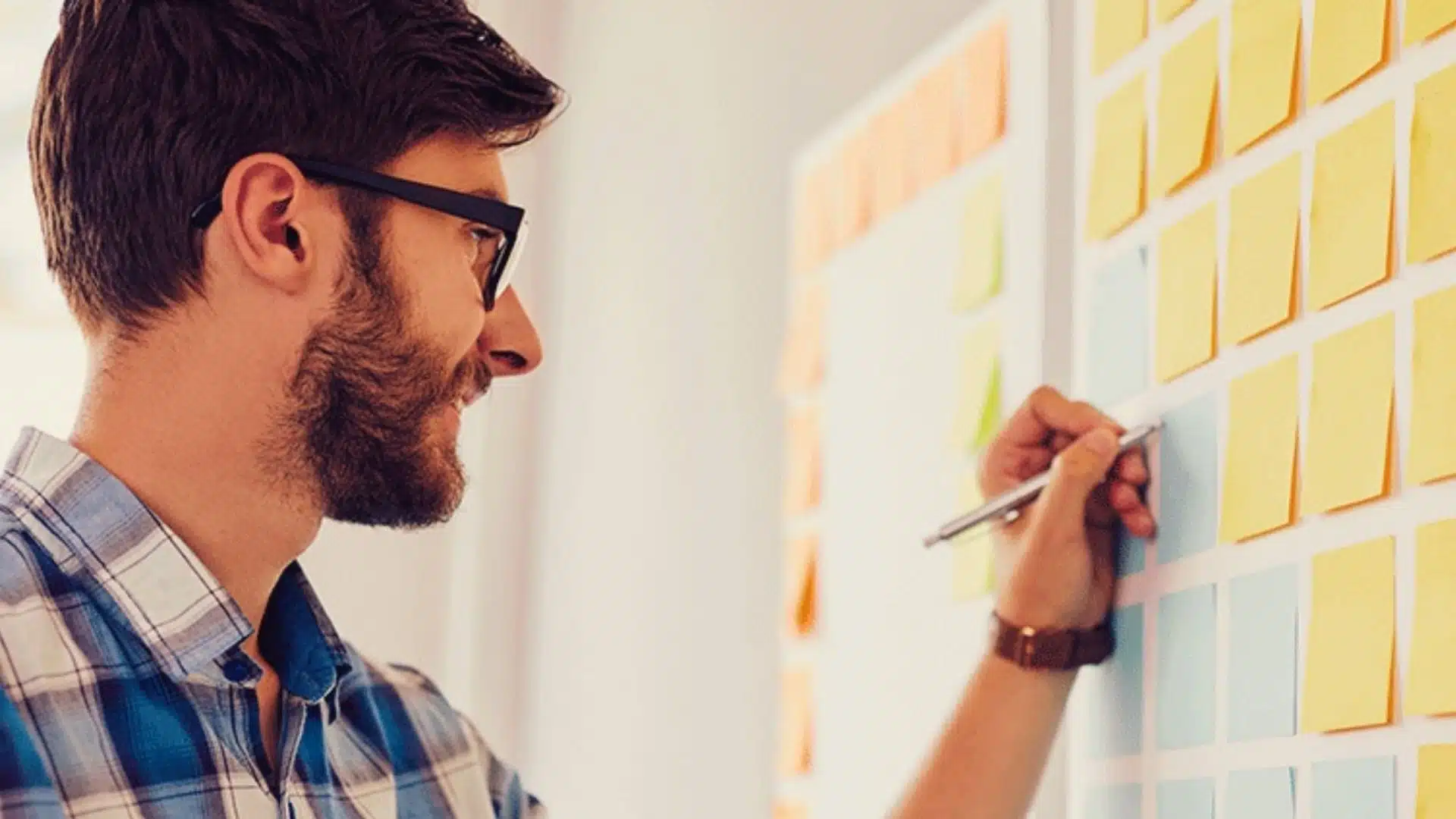 Writing notes on a single sticky note surrounded by a wall of sticky notes.