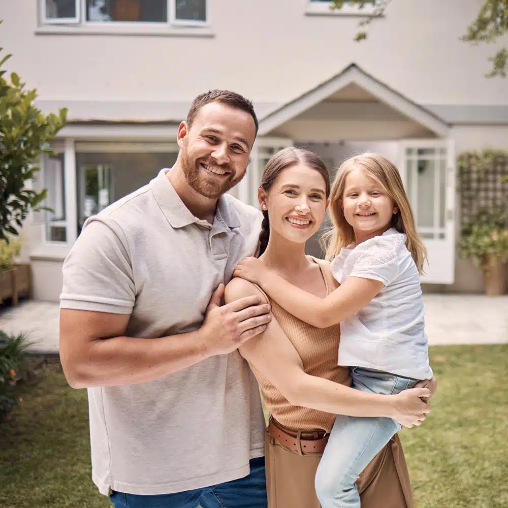 Smiling family standing outside home
