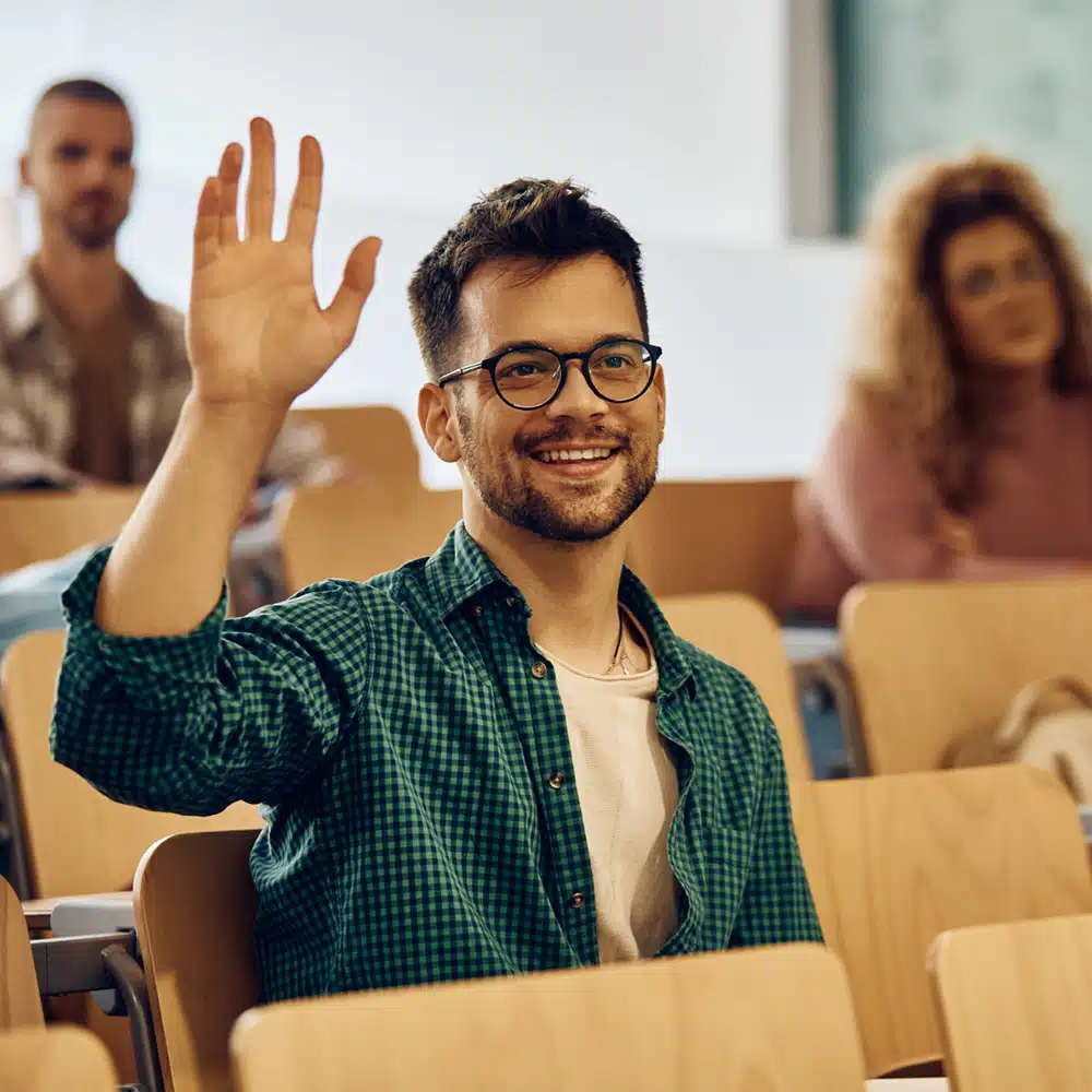 Happy College Student Raising His Hand To Ask Question During Class.