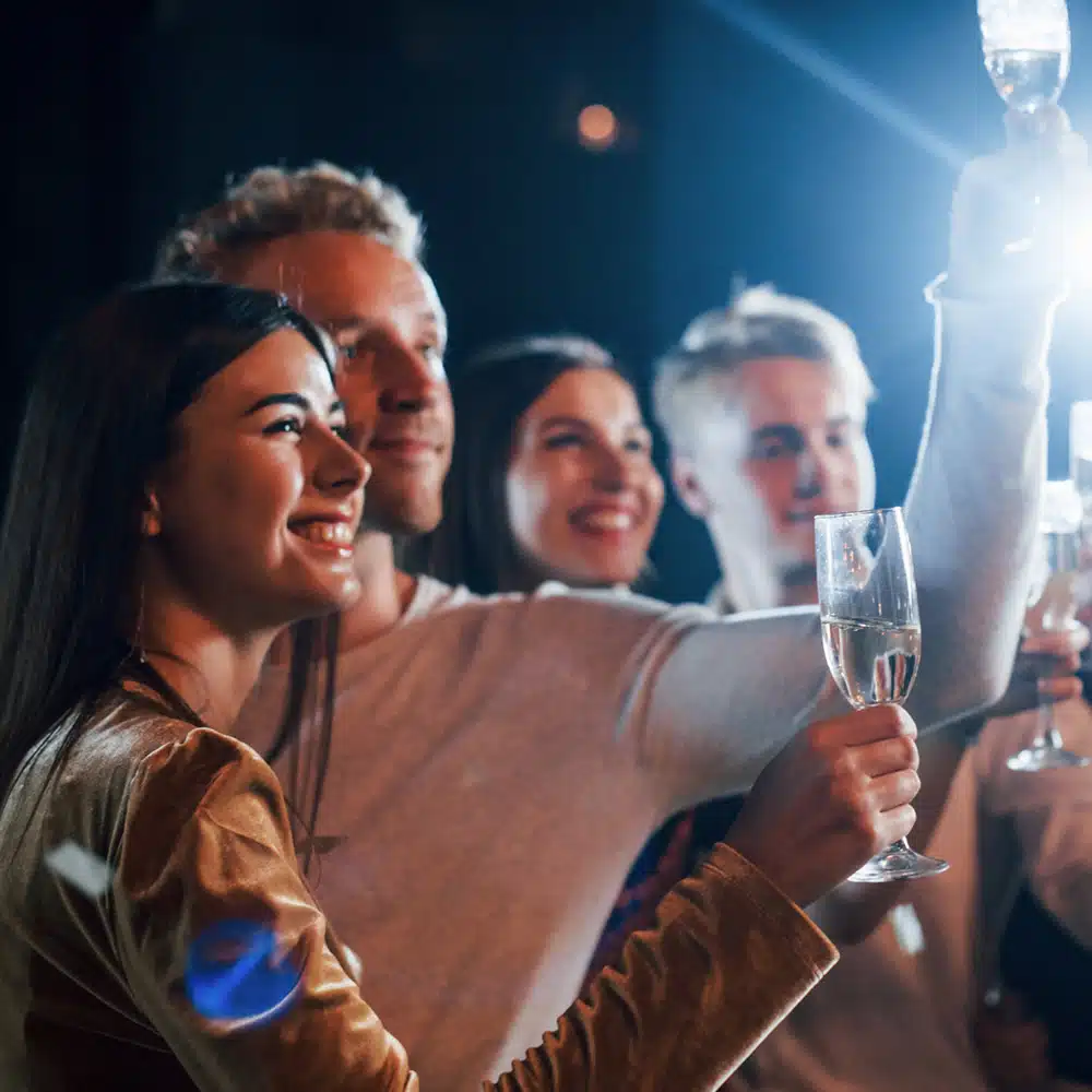 Group Of Cheerful Friends Celebrating New Year Indoors With Drinks In Hands