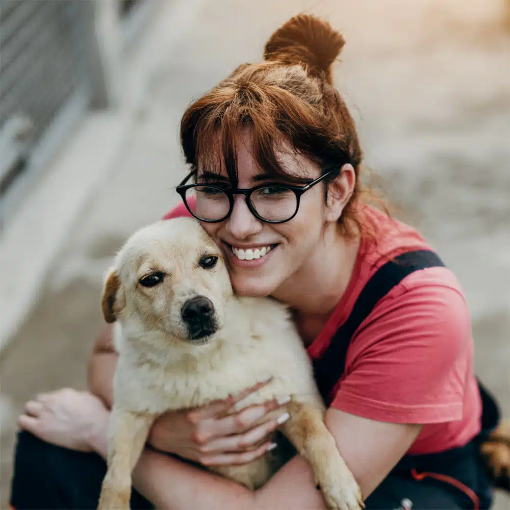 Woman with glasses hugging dog