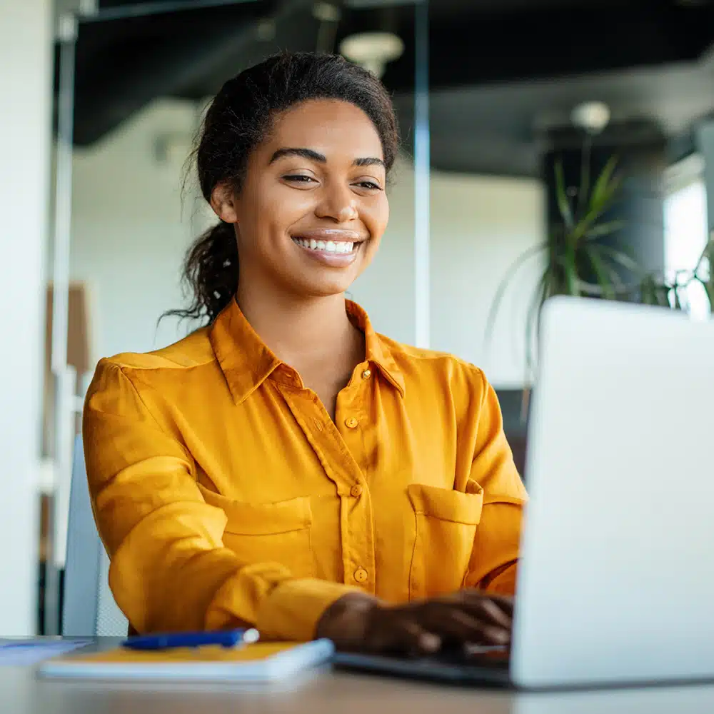 Happy Black Businesswoman Using Laptop Typing And Working Online While Sitting At Workplace In Office, Copy Space