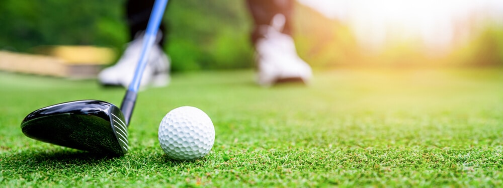 A golf club about to hit a golf ball, representing a popular live auction item 