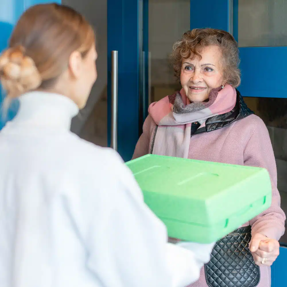 Volunteer Delivering A Meal To Door Of Senior Citizen