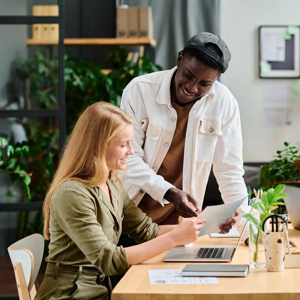 Happy Young Successful Colleagues Discussing Financial Data In Front Of Laptop