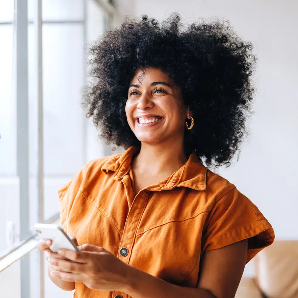 Happy Black Businesswoman Using A Smartphone In A Creative Office