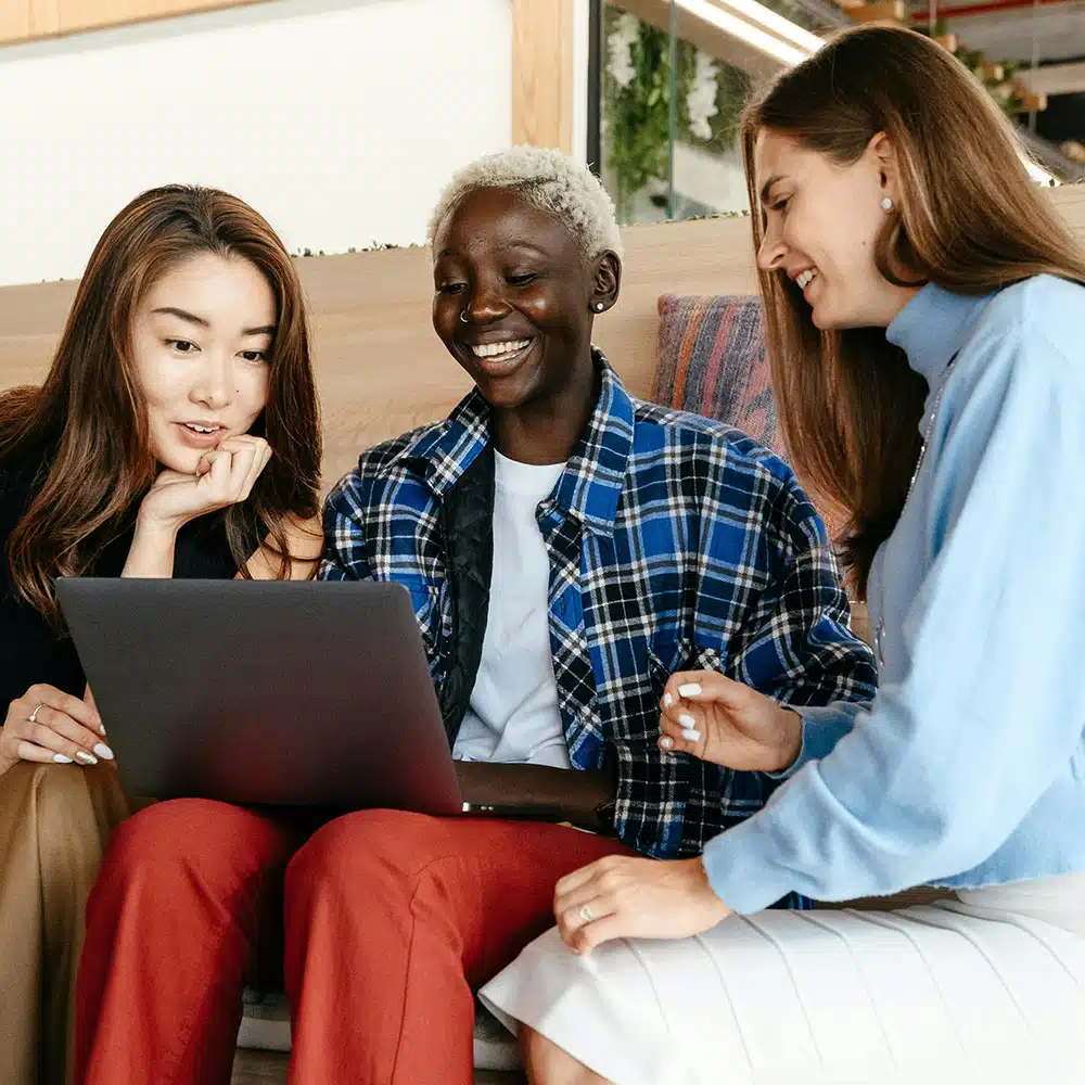 Three women smiling at computer